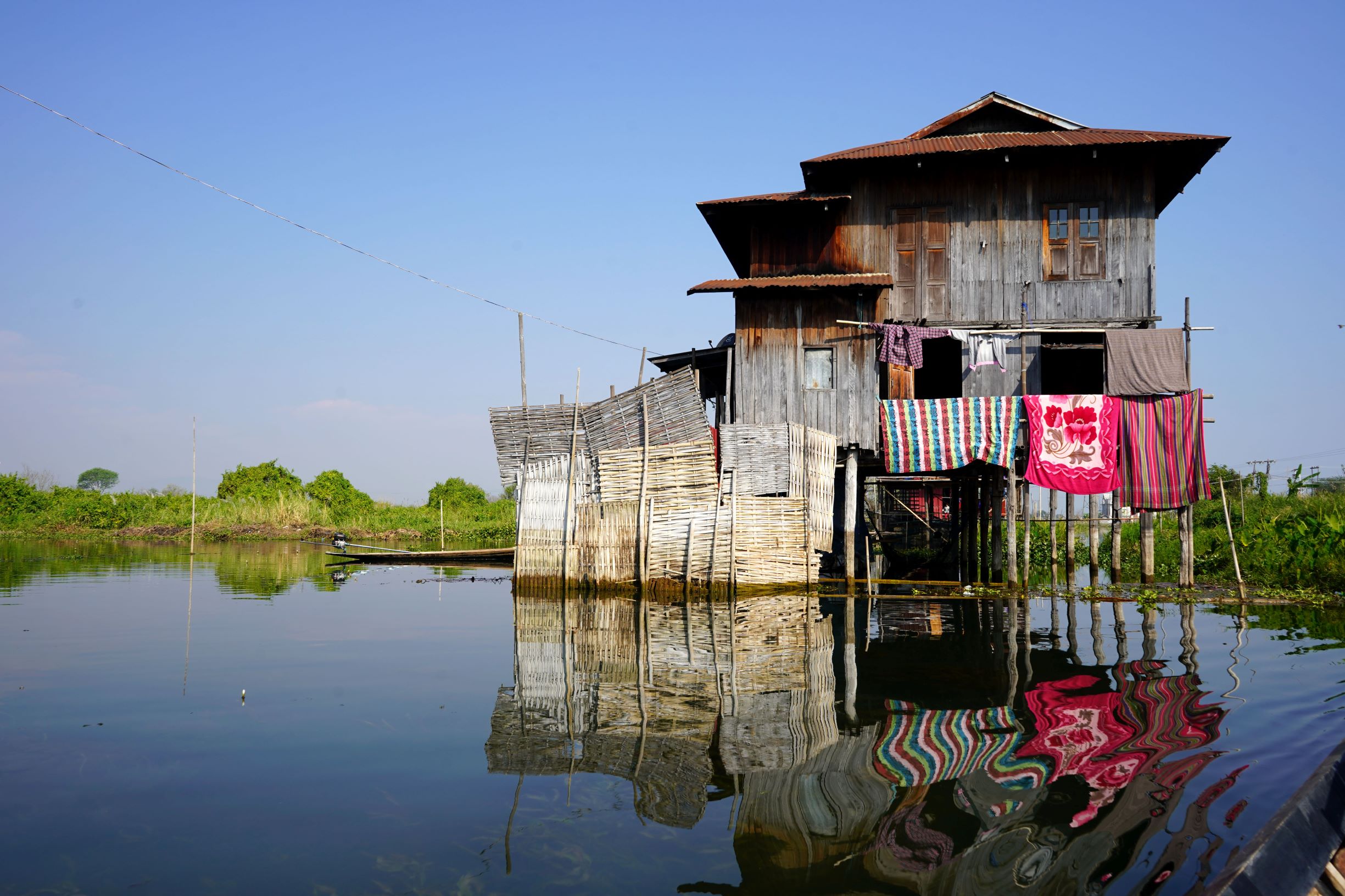 Malerisches schwimmendes Haus am Inle See spiegelt sich im ruhigen Wasser